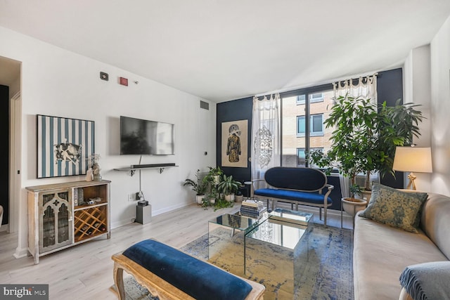 living room with baseboards, visible vents, and wood finished floors