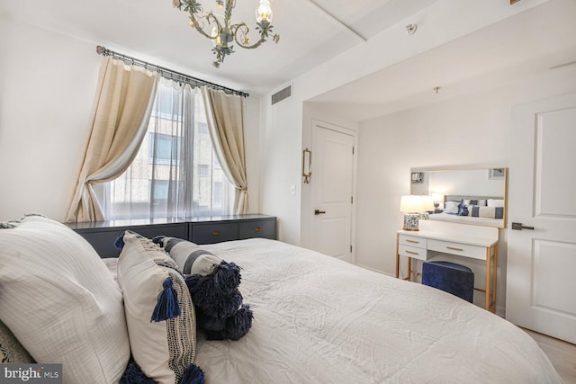 bedroom with visible vents, an inviting chandelier, and wood finished floors