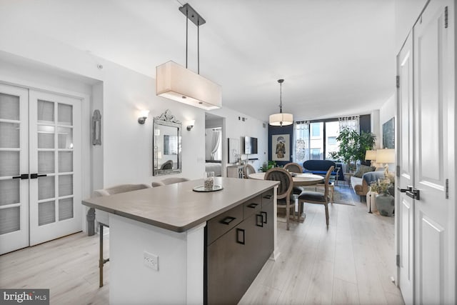 kitchen featuring french doors, a center island, light wood-type flooring, open floor plan, and a breakfast bar
