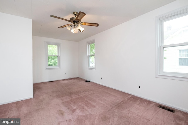 spare room featuring carpet flooring, plenty of natural light, and visible vents