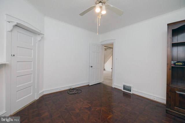 empty room with ornamental molding, baseboards, a ceiling fan, and visible vents