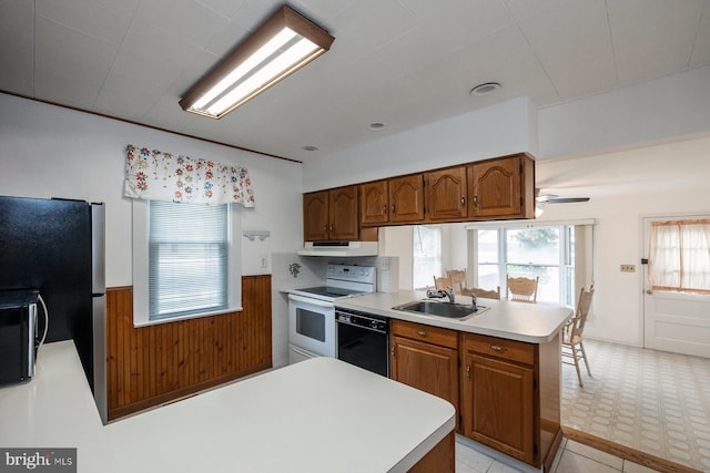 kitchen featuring black appliances, under cabinet range hood, a peninsula, and a sink