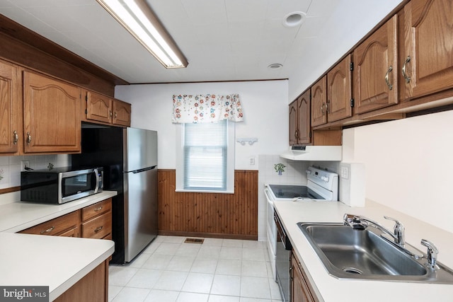 kitchen with brown cabinetry, wainscoting, visible vents, a sink, and appliances with stainless steel finishes