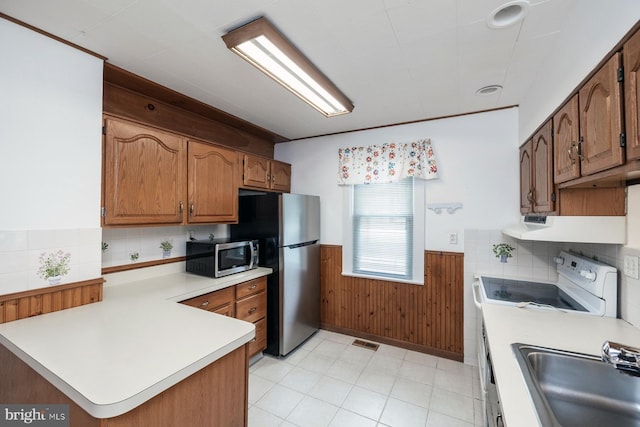 kitchen featuring visible vents, a sink, a wainscoted wall, light countertops, and appliances with stainless steel finishes