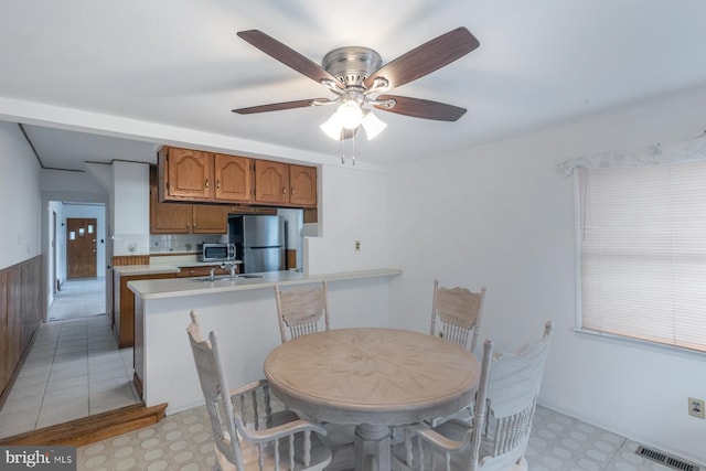 dining space featuring a ceiling fan, light floors, and visible vents