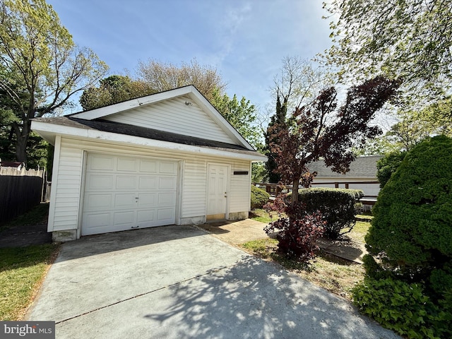 detached garage with concrete driveway and fence