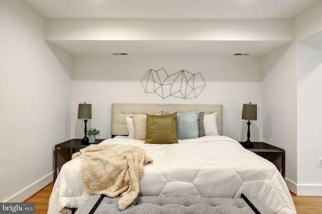 bedroom with baseboards, wood finished floors, and visible vents