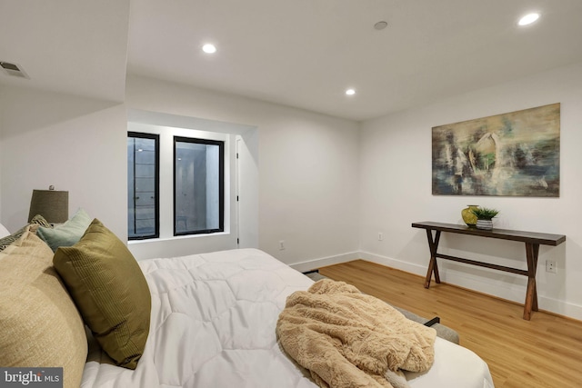 bedroom with baseboards, recessed lighting, wood finished floors, and visible vents
