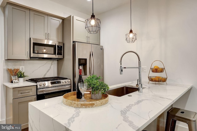 kitchen with light stone countertops, tasteful backsplash, a sink, gray cabinetry, and stainless steel appliances