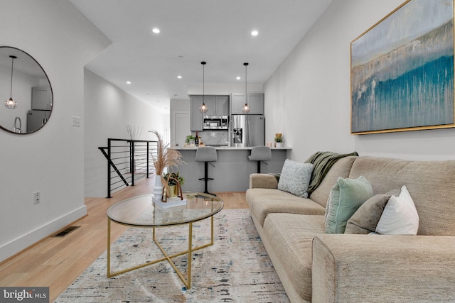 living room with visible vents, recessed lighting, light wood finished floors, and baseboards
