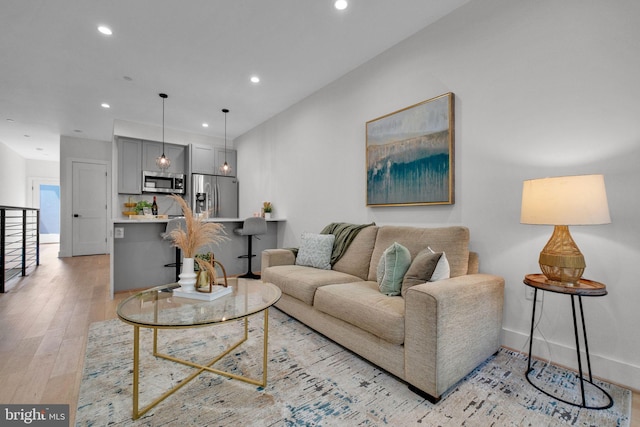 living room with recessed lighting, light wood-style floors, and baseboards