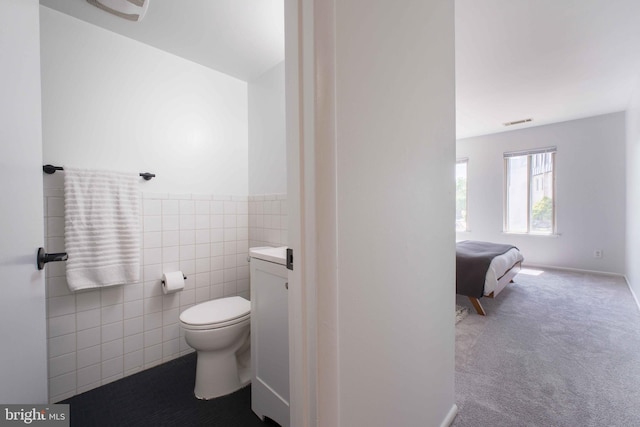 bathroom featuring visible vents, a wainscoted wall, toilet, and tile walls