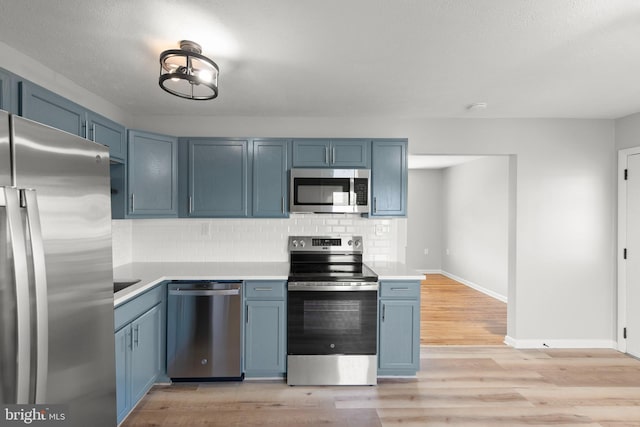 kitchen featuring blue cabinets, tasteful backsplash, and stainless steel appliances