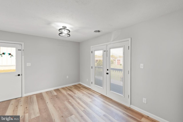 entryway featuring visible vents, baseboards, a textured ceiling, french doors, and light wood finished floors