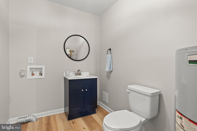 half bath with wood finished floors, vanity, baseboards, toilet, and water heater