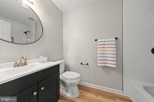 full bath featuring vanity, wood finished floors, toilet, baseboards, and shower / bathing tub combination