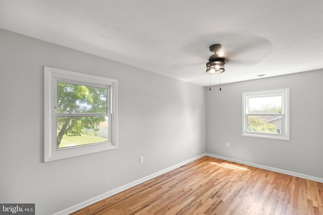 unfurnished room with baseboards, light wood-style flooring, ceiling fan, and a wealth of natural light