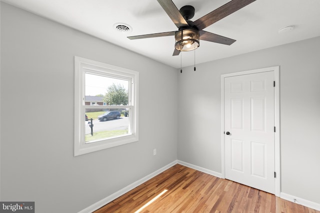 spare room with light wood-style floors, baseboards, ceiling fan, and visible vents