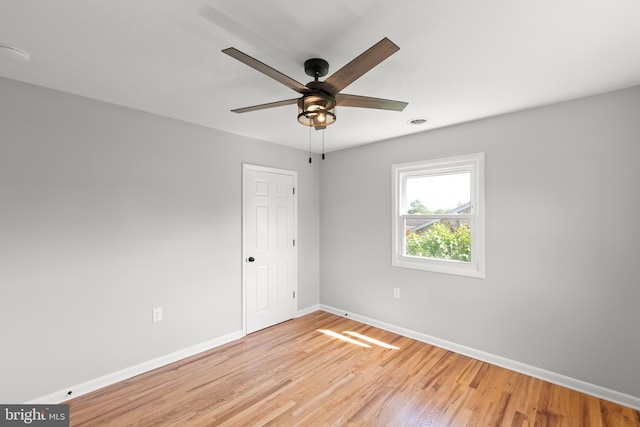 empty room with baseboards, a ceiling fan, light wood finished floors, and visible vents