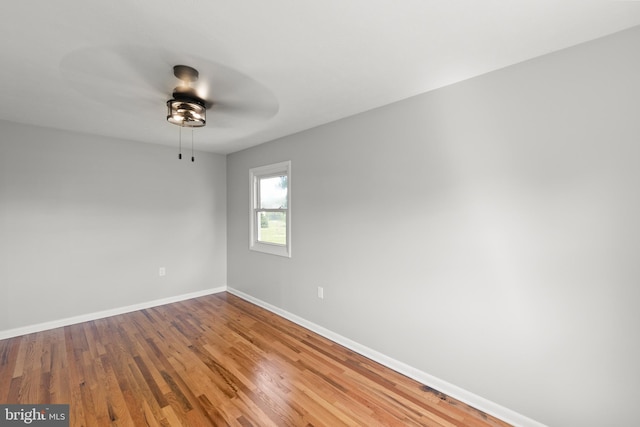 spare room featuring baseboards, ceiling fan, and wood finished floors