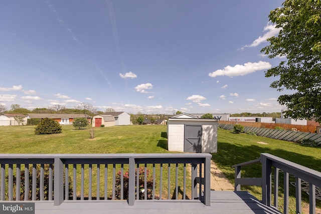 wooden deck with a storage unit, an outdoor structure, fence, and a yard