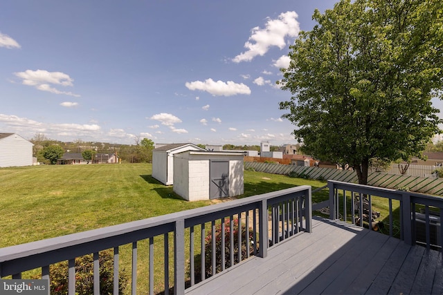 wooden terrace featuring a storage shed, a yard, and an outbuilding