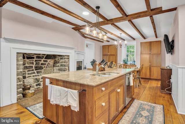 kitchen with brown cabinetry, dishwasher, a sink, beamed ceiling, and light wood-style flooring