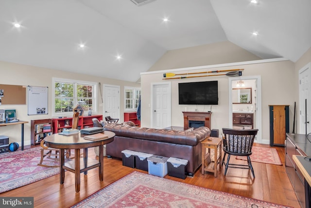living area featuring baseboards, a fireplace, vaulted ceiling, and hardwood / wood-style floors