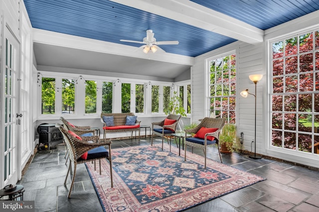 sunroom featuring beamed ceiling and stone tile floors