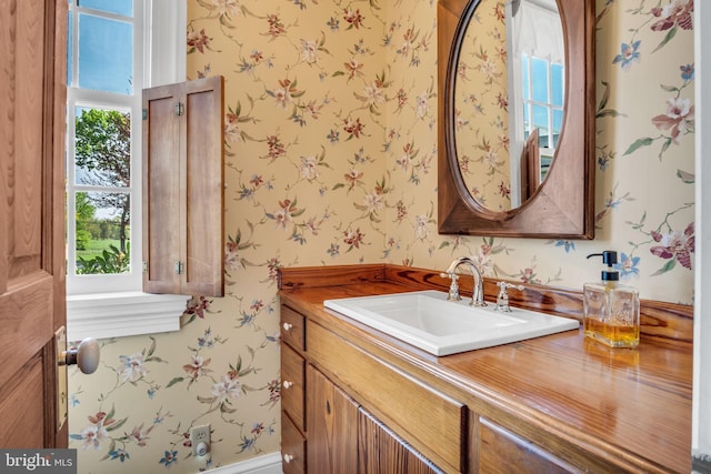 bathroom featuring vanity and wallpapered walls