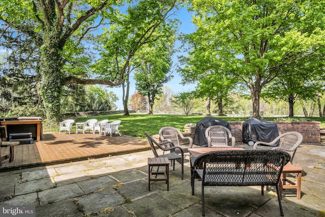 view of patio / terrace with a hot tub, a deck, and a grill