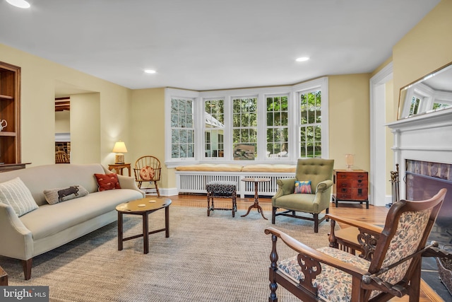 living room featuring recessed lighting, radiator, wood finished floors, and a fireplace