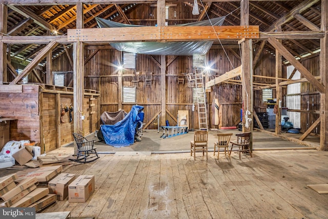 misc room with high vaulted ceiling, wooden walls, and hardwood / wood-style flooring