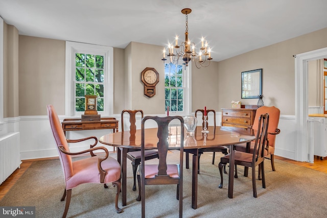 dining room with radiator, wood finished floors, a notable chandelier, and wainscoting