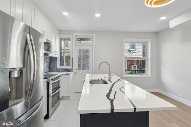 6227 Delancey St, Philadelphia, PA 19143 - kitchen with a kitchen island with sink, appliances with stainless steel finishes, tasteful backsplash, a sink, and light countertops