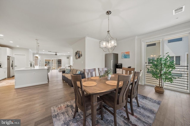 dining room featuring visible vents, crown molding, ceiling fan with notable chandelier, recessed lighting, and light wood-style flooring