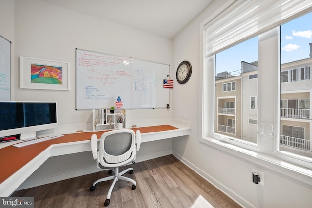 office area with built in study area, baseboards, and wood finished floors