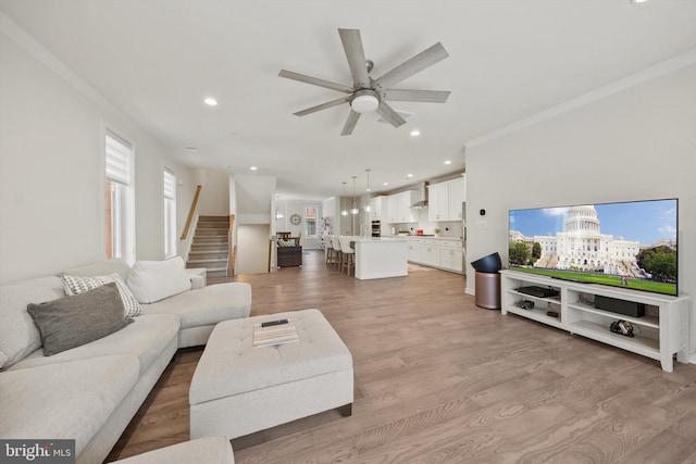 living area featuring ornamental molding, stairs, recessed lighting, a ceiling fan, and light wood finished floors