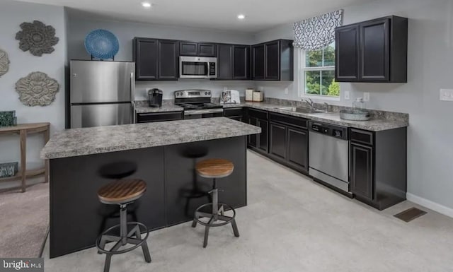 kitchen featuring a sink, a center island, stainless steel appliances, a kitchen bar, and visible vents