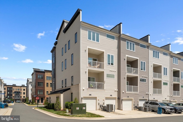 view of building exterior with an attached garage and central air condition unit
