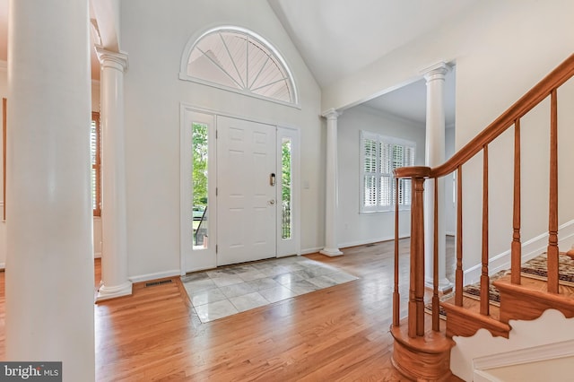entrance foyer featuring ornate columns, stairs, wood finished floors, and visible vents