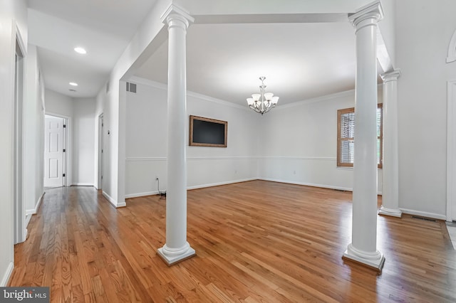 interior space featuring crown molding, light wood-type flooring, and ornate columns