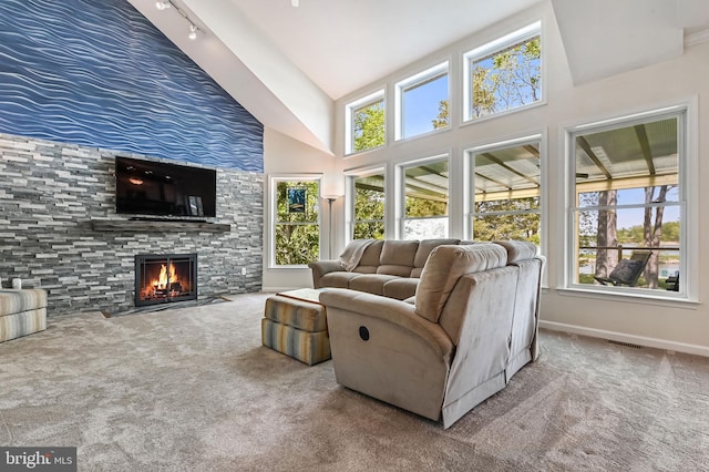 carpeted living room with high vaulted ceiling, visible vents, baseboards, and a fireplace