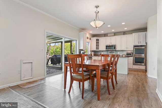 dining area featuring light wood-style floors, baseboards, ornamental molding, and recessed lighting