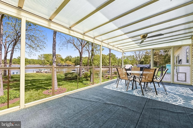 sunroom / solarium with a water view, ceiling fan, and outdoor dining area