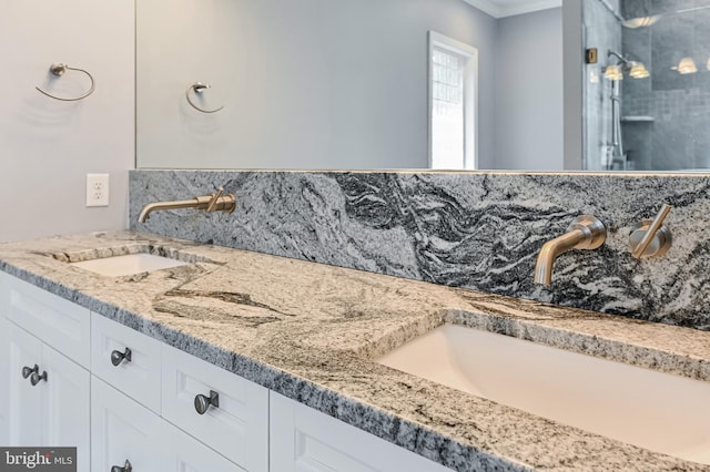 bathroom with double vanity, a sink, and tiled shower