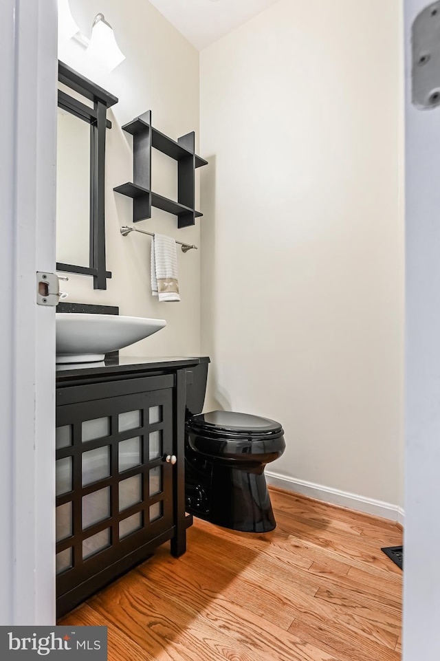 bathroom featuring baseboards, wood finished floors, and toilet