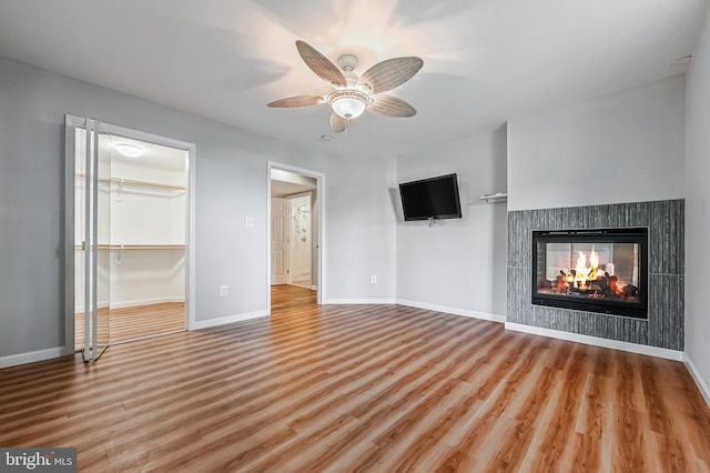 unfurnished living room featuring a multi sided fireplace, baseboards, and wood finished floors