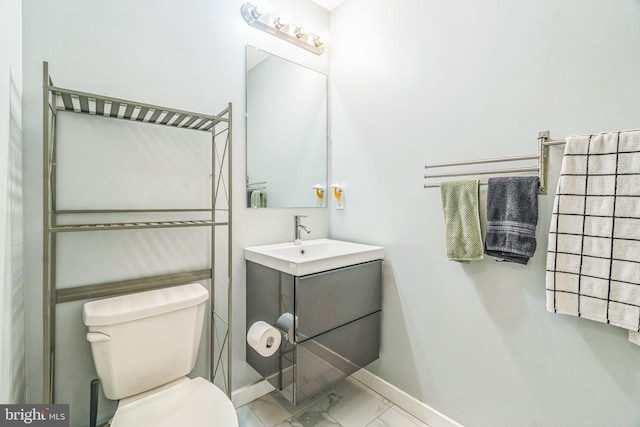 half bath with toilet, baseboards, marble finish floor, and vanity