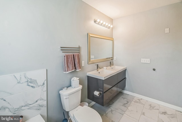 bathroom featuring double vanity, marble finish floor, toilet, baseboards, and a sink